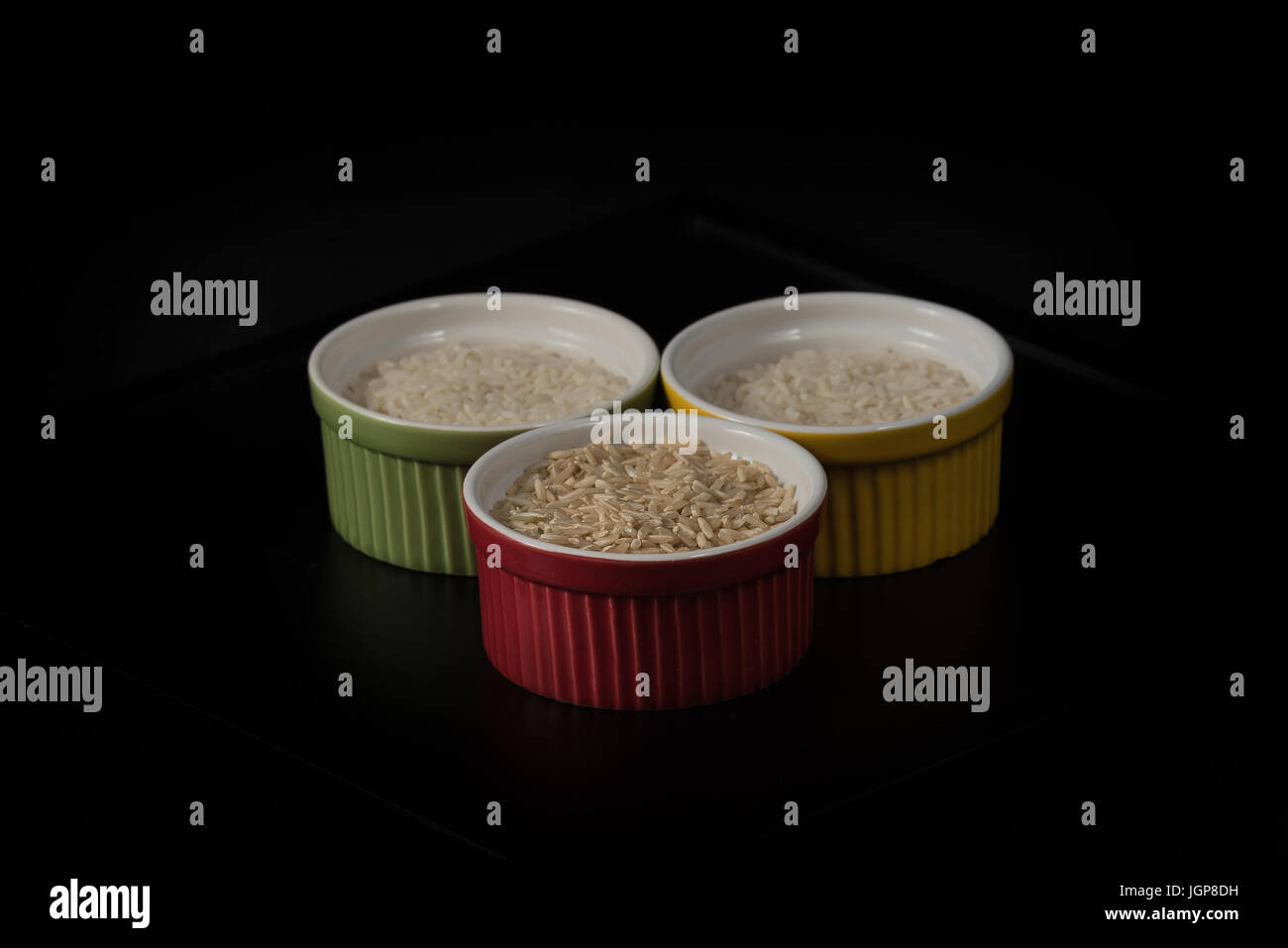 White and brown grains of rice in multicolored ramekins Stock Photo