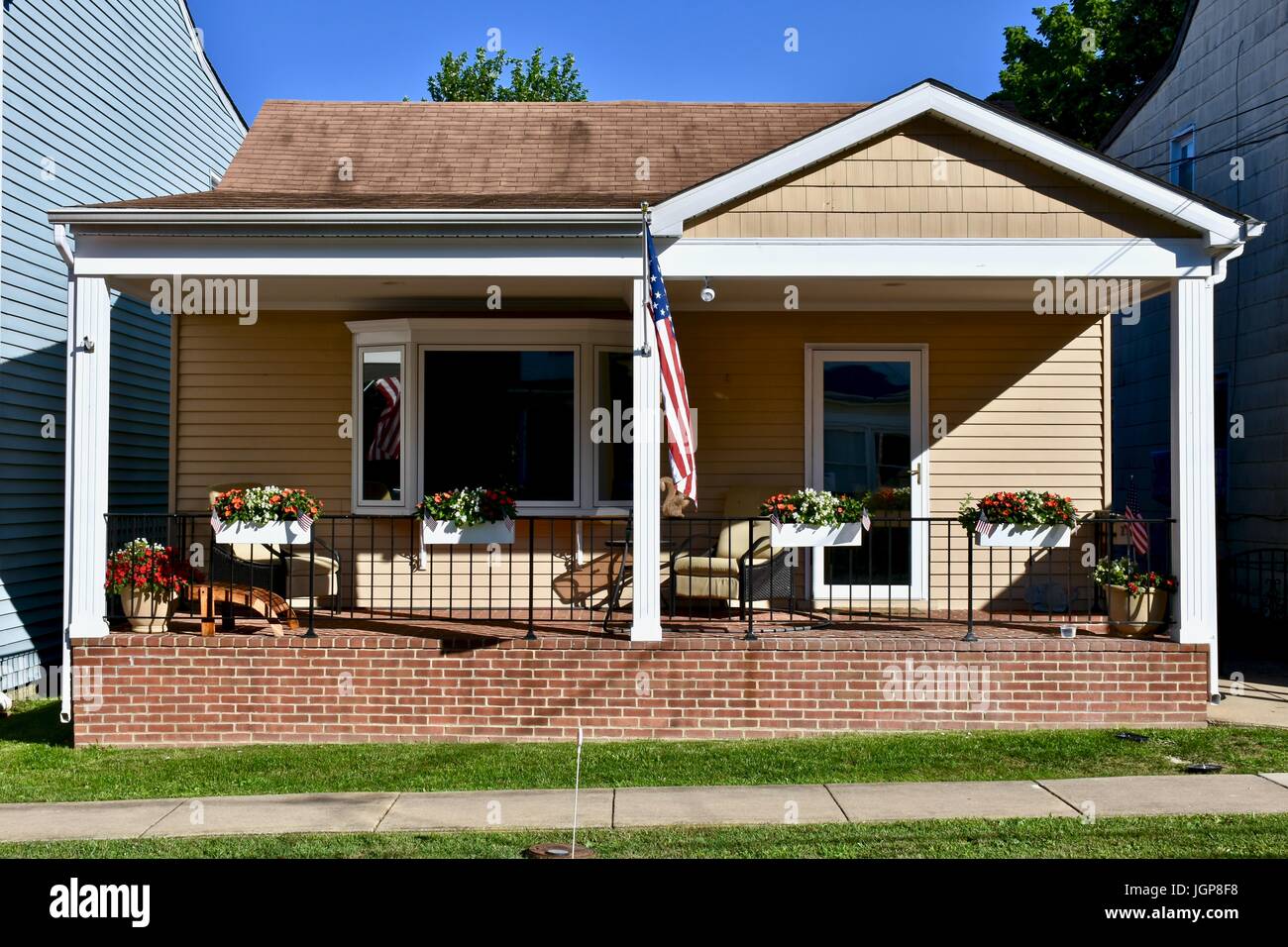 Small house with American flag hanging from front porch Stock Photo