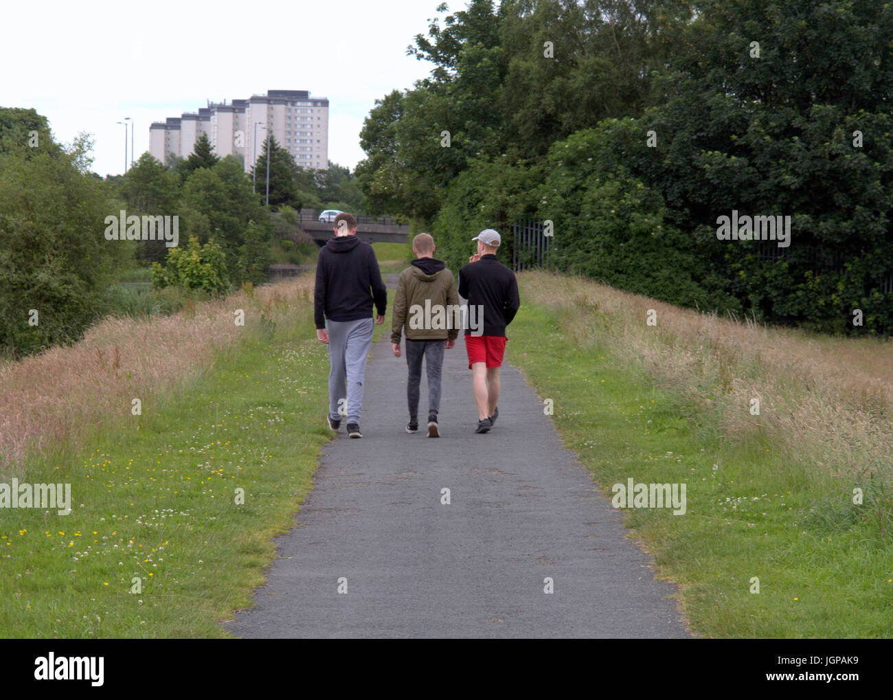 three young guys students teenagers boys viewed from behind in a cityscene setting om the canal towpath  Drumchapel Stock Photo