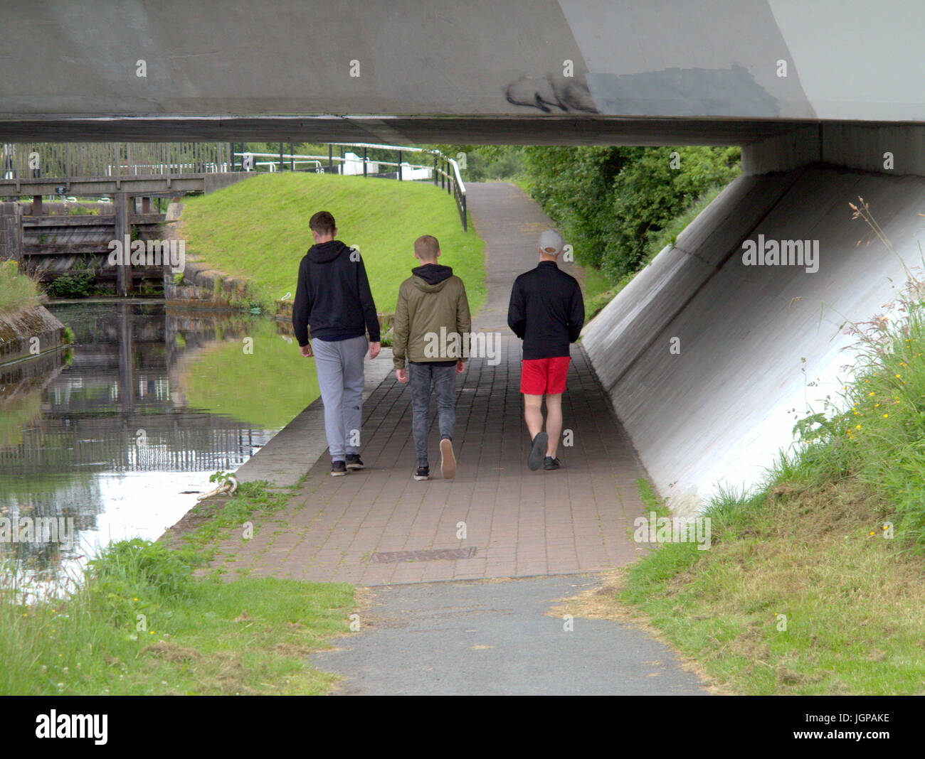three young guys students teenagers boys viewed from behind in a cityscene setting om the canal towpath  Drumchapel Stock Photo