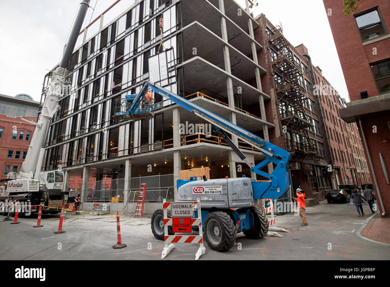 cherry picker elevated platform guiding building panels on construction site Boston USA Stock Photo