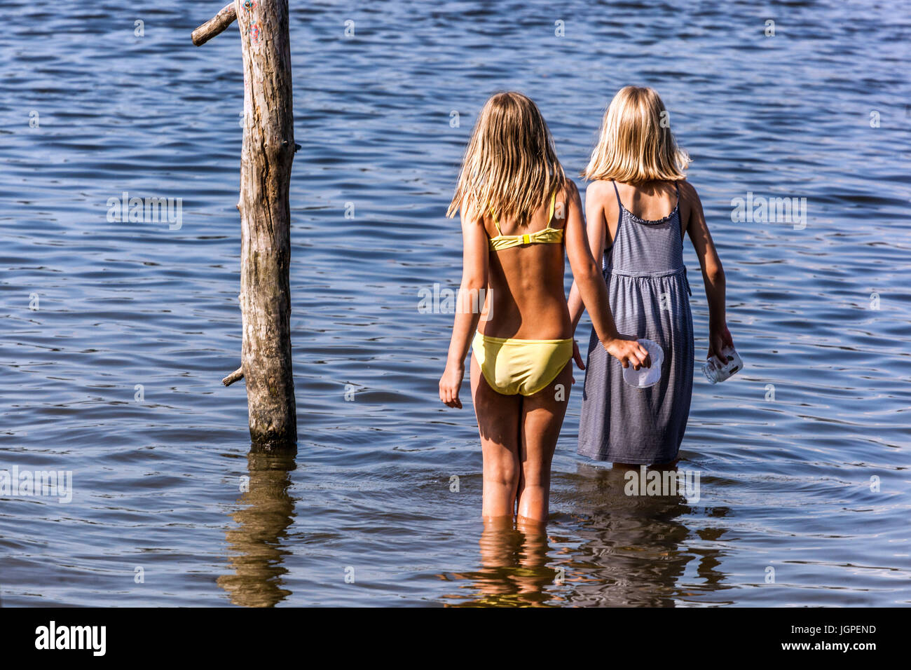 Two girls standing in the water and looking in the distance Stock Photo