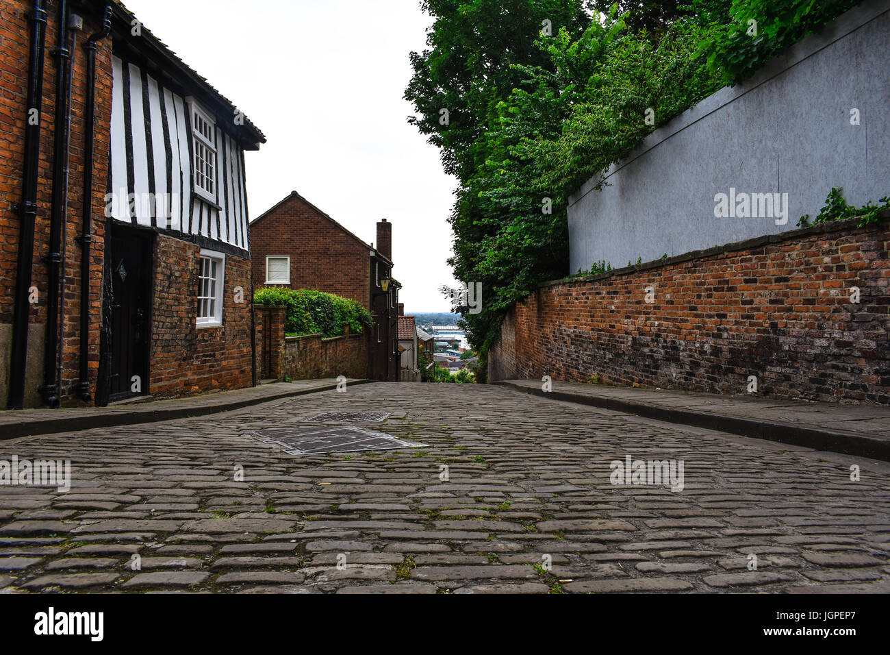 Top of the steep hill in Lincoln, looking back down into the town down a old brick road with old buildings Stock Photo