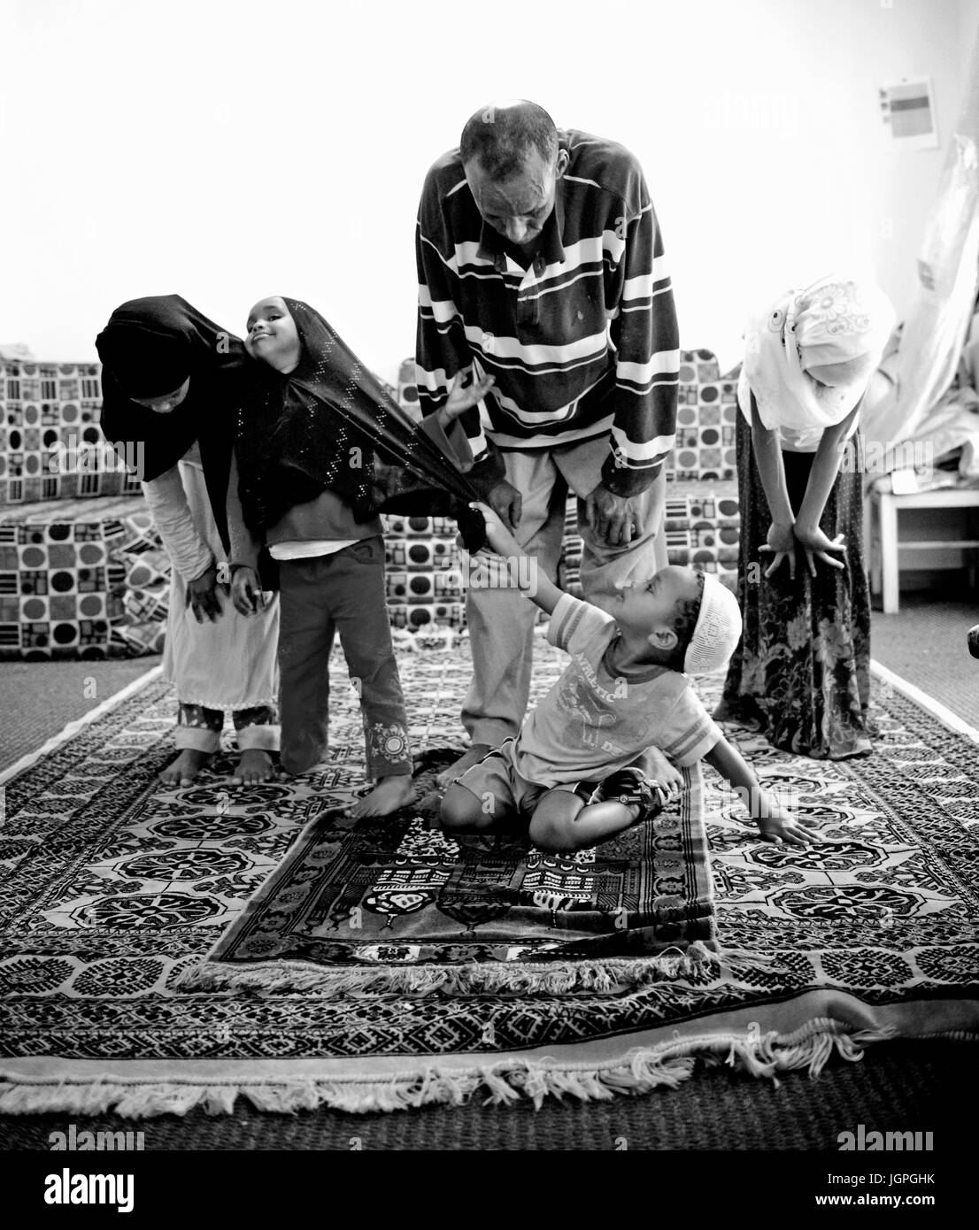 Somali refugee family in their new home in Portland, Oregon - a young boy grabs his sisters hijab during Muslim family prayer. Stock Photo