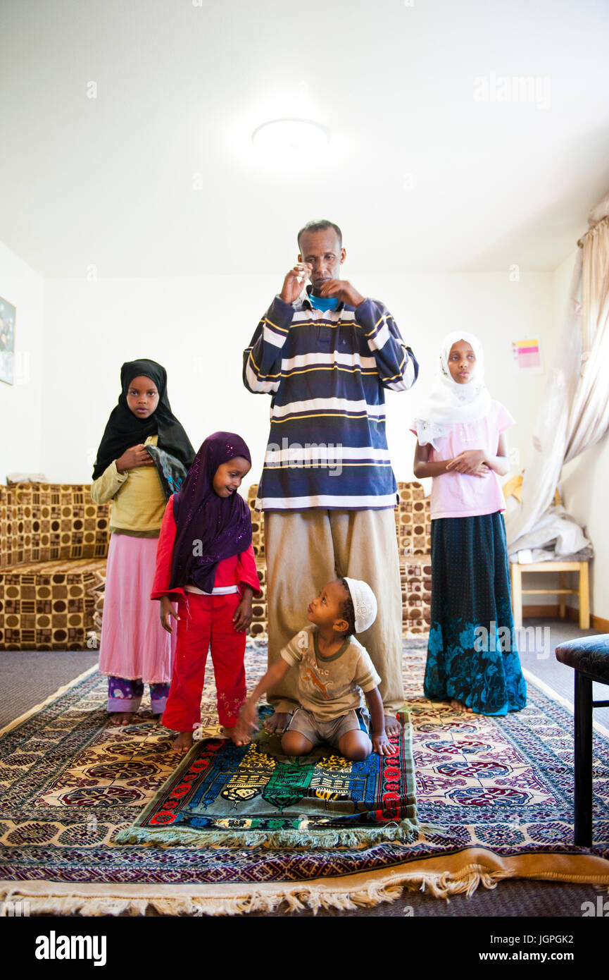 Somali refugee family in their new home in Portland, Oregon - a young boy grabs his sisters hijab during Muslim family prayer. Stock Photo