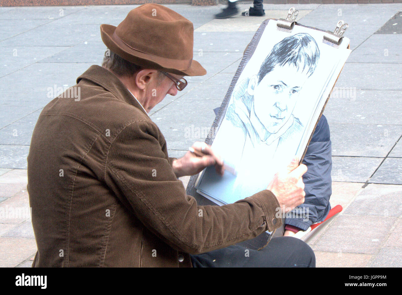 street artist on Buchanan street Glasgow drawing a portrait of a young boy Stock Photo