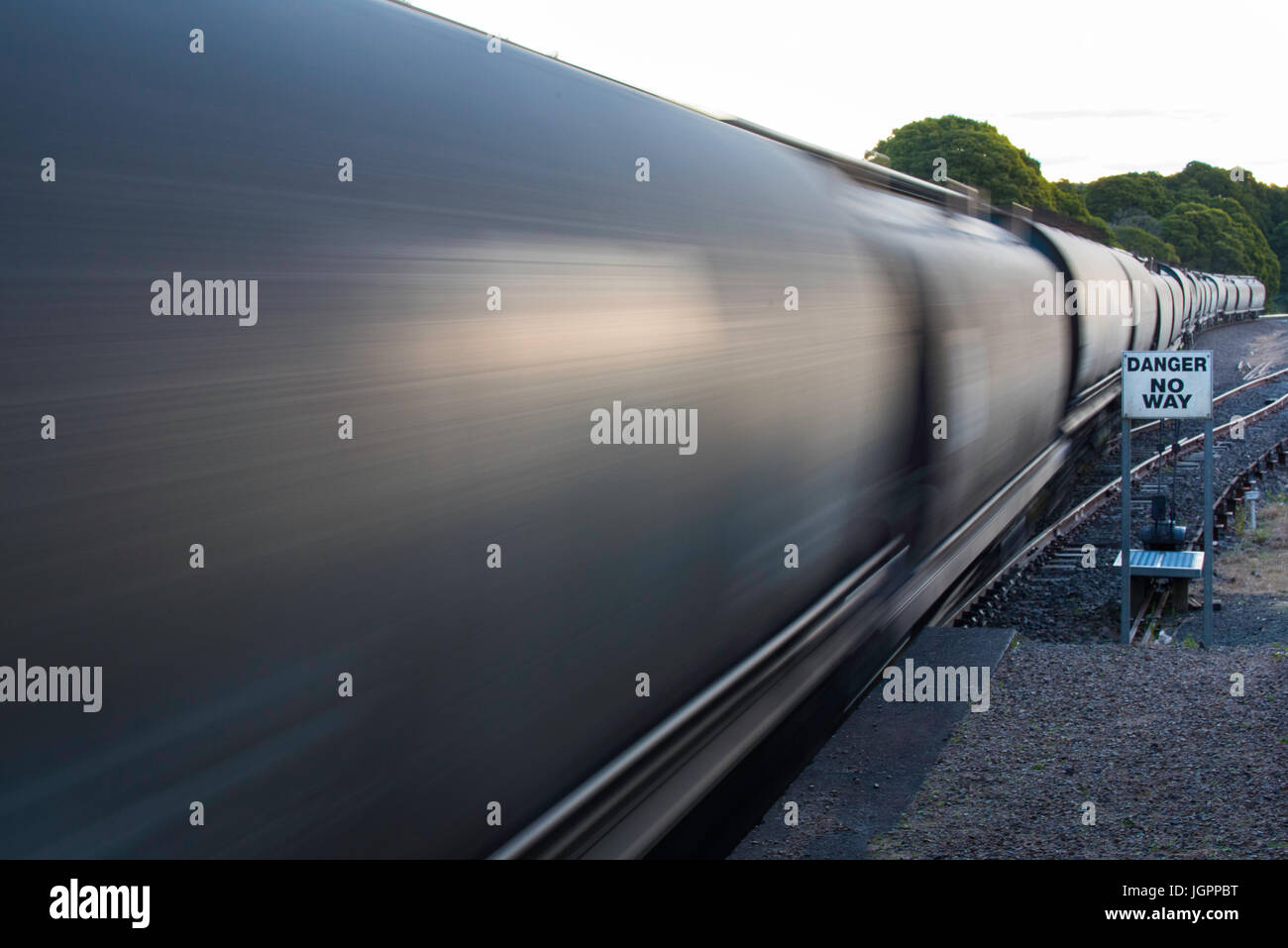 Rail freight cars speed through a country railway station carrying coal for export from New South Wales, Australia Stock Photo