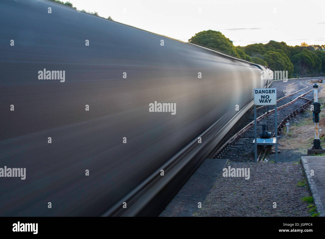 Rail freight cars speed through a country railway station carrying coal for export from New South Wales, Australia Stock Photo