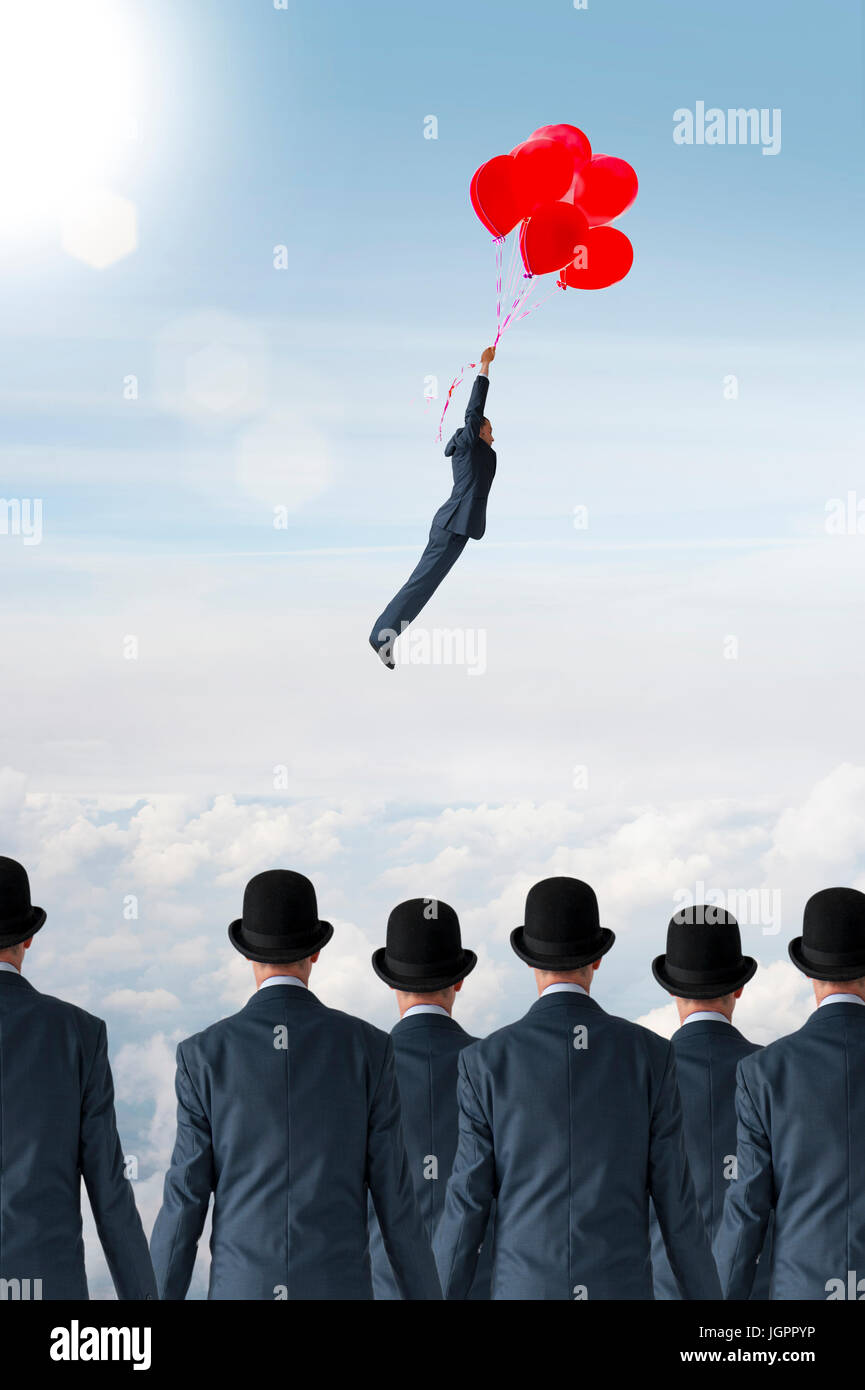 business individuality concept businessman flying away from crowd with balloons Stock Photo