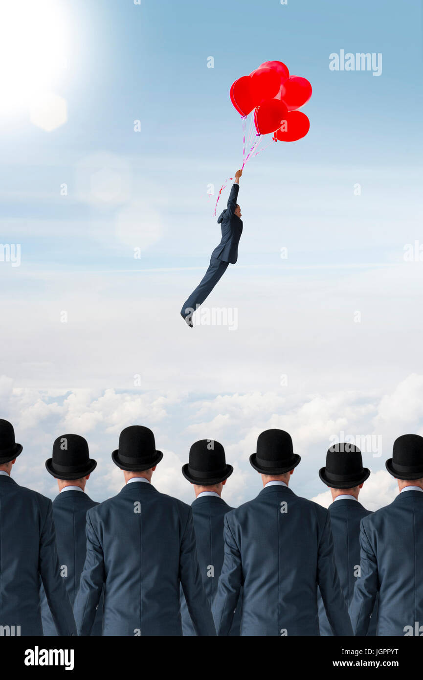 business individuality concept businessman flying away from crowd with balloons Stock Photo