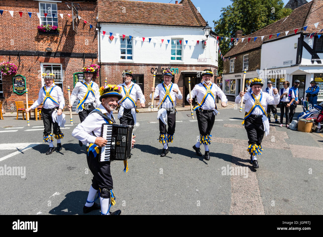 Traditional English folk dancers, Yateley Morris side dancing with accordion in the street in medieval town, Sandwich during folk and ale festival. Stock Photo