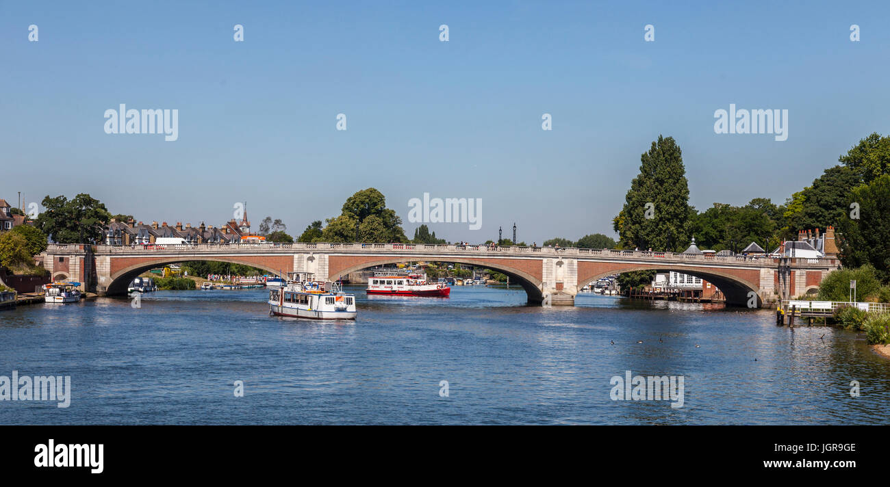 Hampton Court Bridge (1933) over the River Thames between Hampton, London and East Molesey, Surrey with busy ferry boats and a queue of passengers. Stock Photo