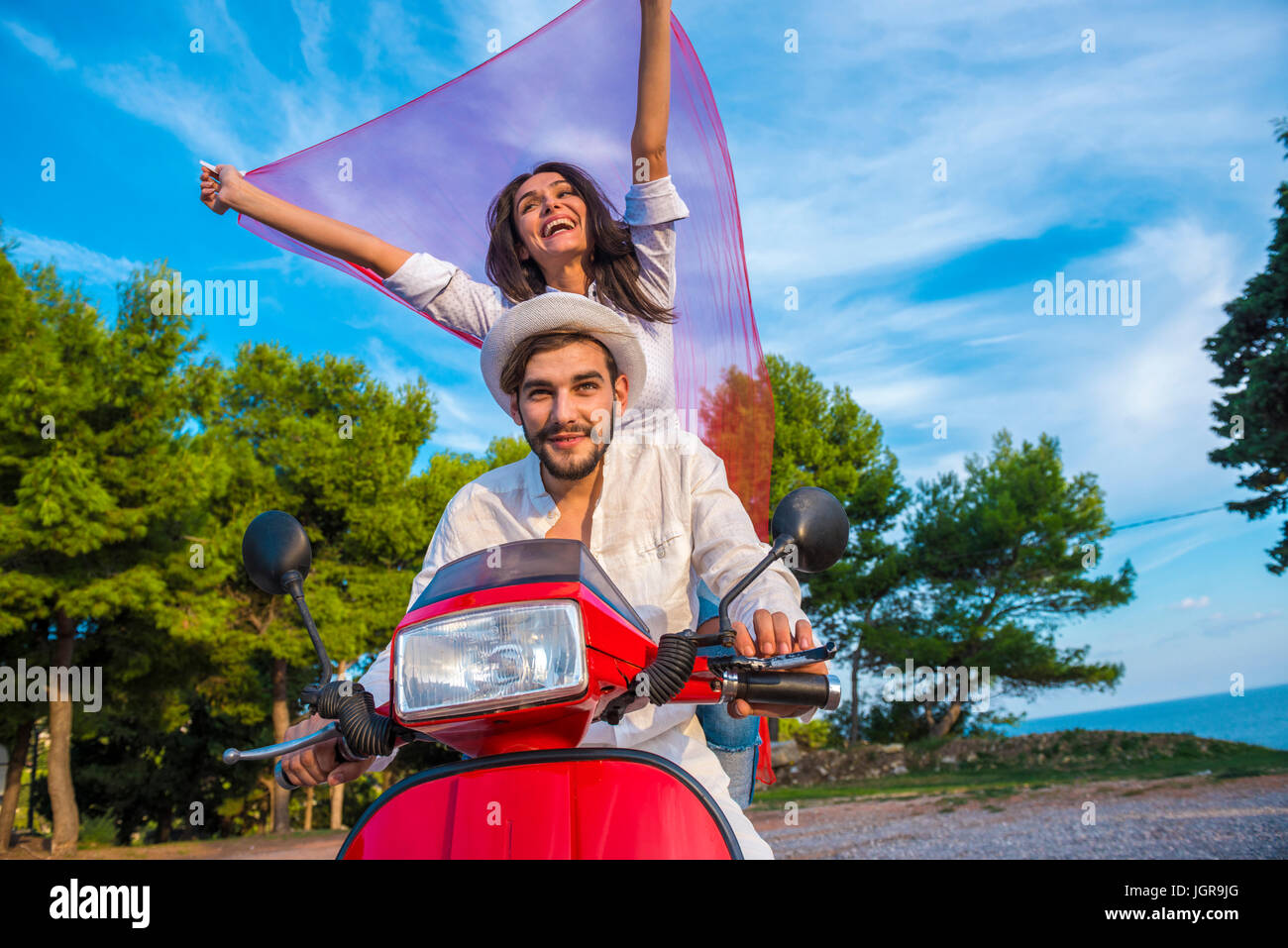 Happy smiling and screaming male tourist in helmet and sunglasses riding motorbike  scooter during his tropical vacation under palm trees Stock Photo - Alamy