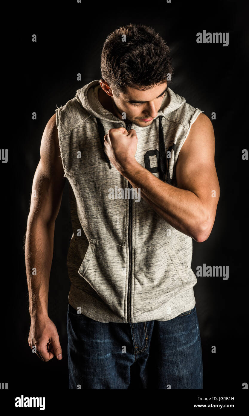 Young fit man flexing his bicep isolated on black background Stock Photo