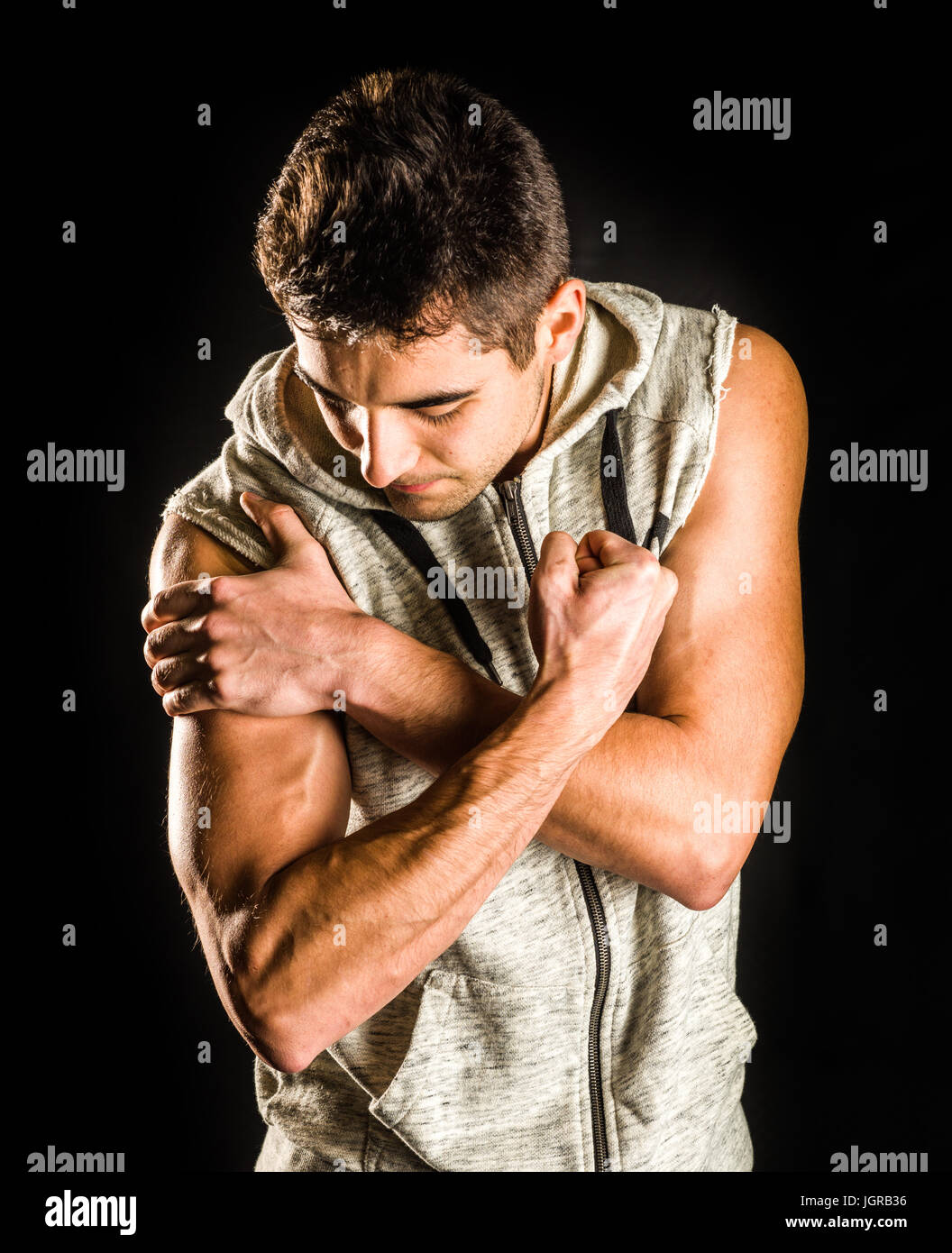 Young fit man flexing his bicep isolated on black background Stock Photo