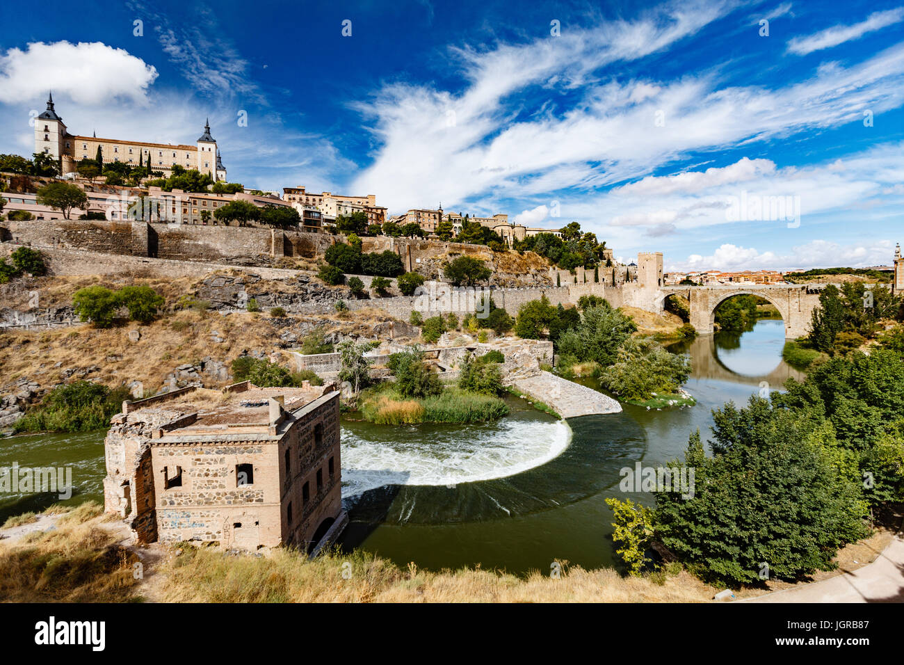 Panoramic view of Toledo Spain on a sunny summer day. Ancient stone walls and houses, blue sky and red-hot earth. Stock Photo