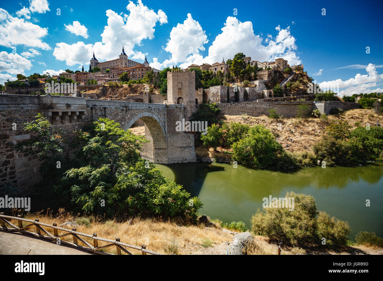 Panoramic view of Toledo Spain on a sunny summer day. Ancient stone walls and houses, blue sky and red-hot earth. Stock Photo