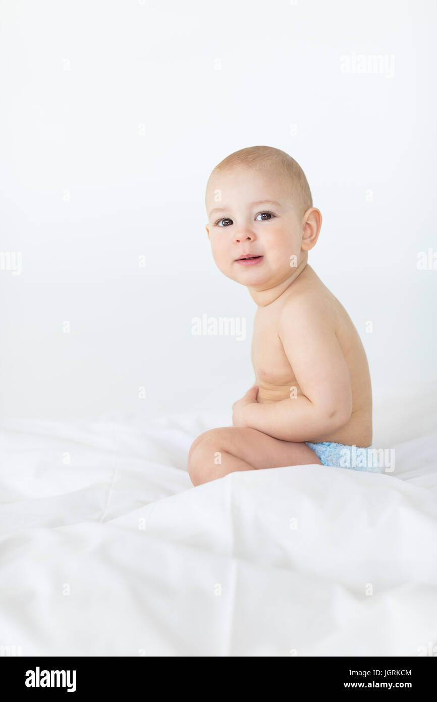 adorable baby boy sitting on bed isolated on white, 1 year old baby