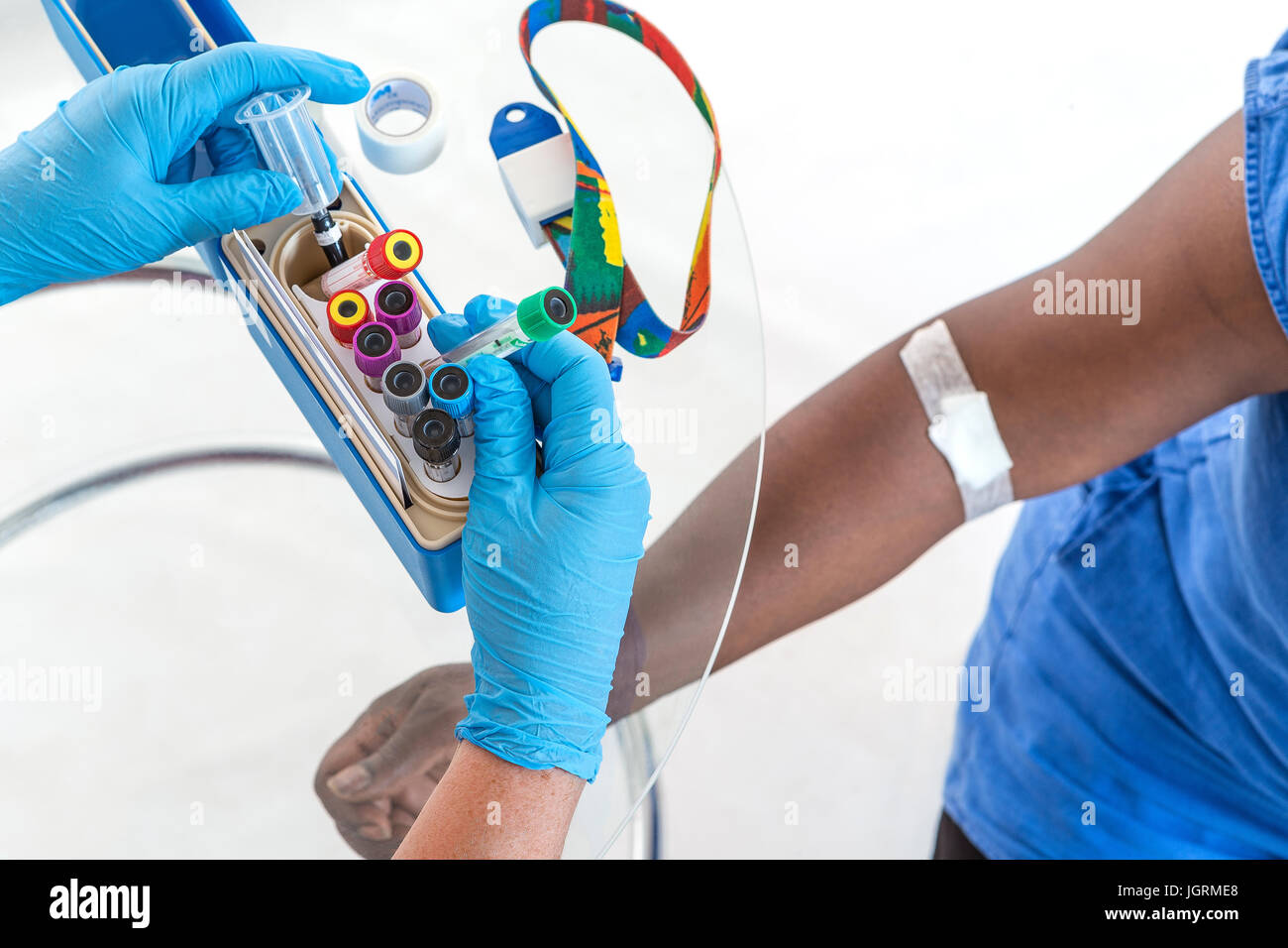hands of nurse organising her bloods test tubes box for laboratory with patient arm on background Stock Photo
