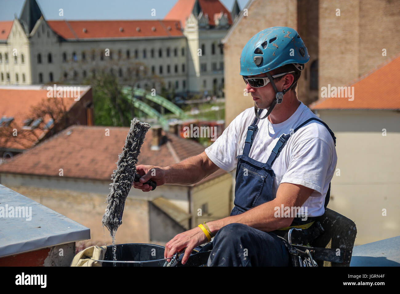 Industrial climbing - Facade Cleaning Service.  Worker preparing for window cleaning on high skyscraper. Stock Photo