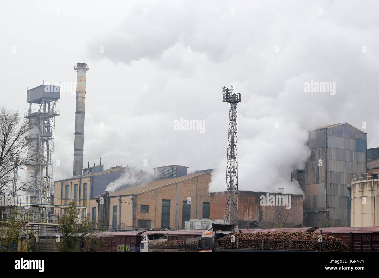 Processing sugar beet in sugar refinery. Factory chimneys emitting smoke to the air. Stock Photo