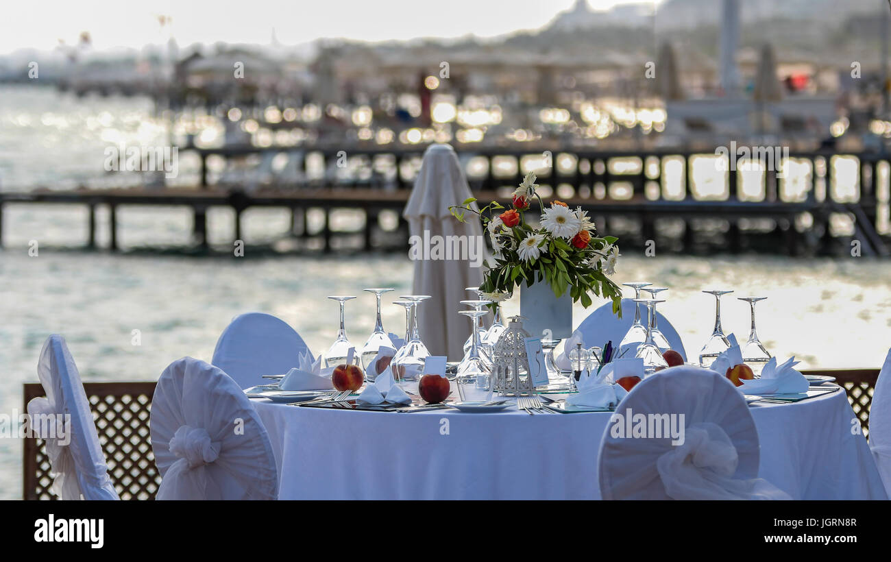 Luxury wedding reception by the sea. Wedding table with a beautiful sea view.  Wedding reception place ready for guests. Stock Photo