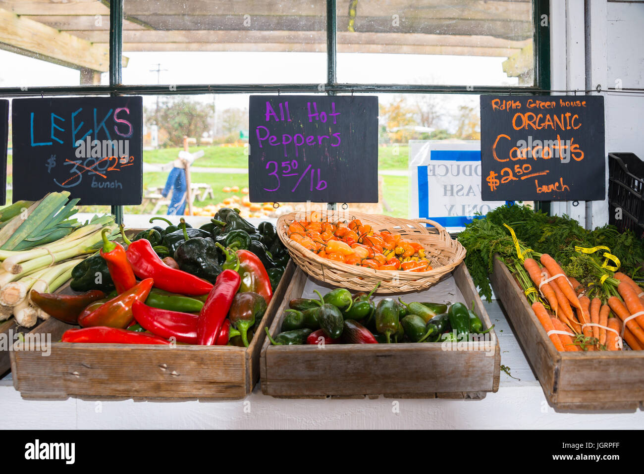 Display of Leeks, Hot Peppers, and Organic Carrots with Signs with Prices in Old Farm Roadside Stand Stock Photo