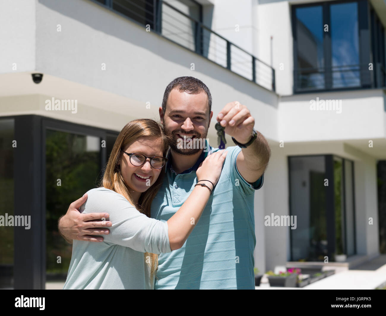 Portrait of a happy young couple hugging in front of their new luxury ...