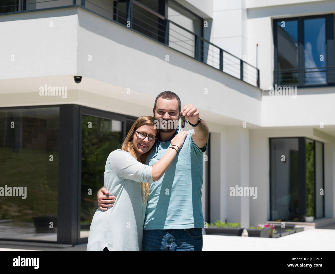 Portrait of a happy young couple hugging in front of their new luxury ...