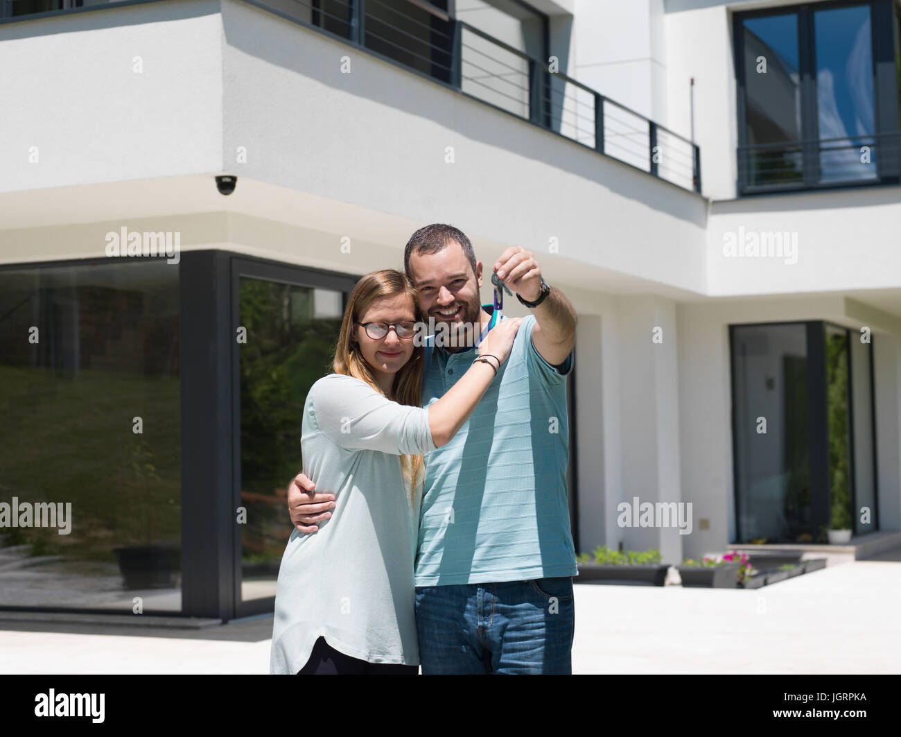 Portrait of a happy young couple hugging in front of their new luxury ...