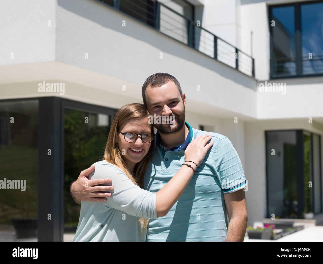 Portrait of a happy young couple hugging in front of their new luxury ...