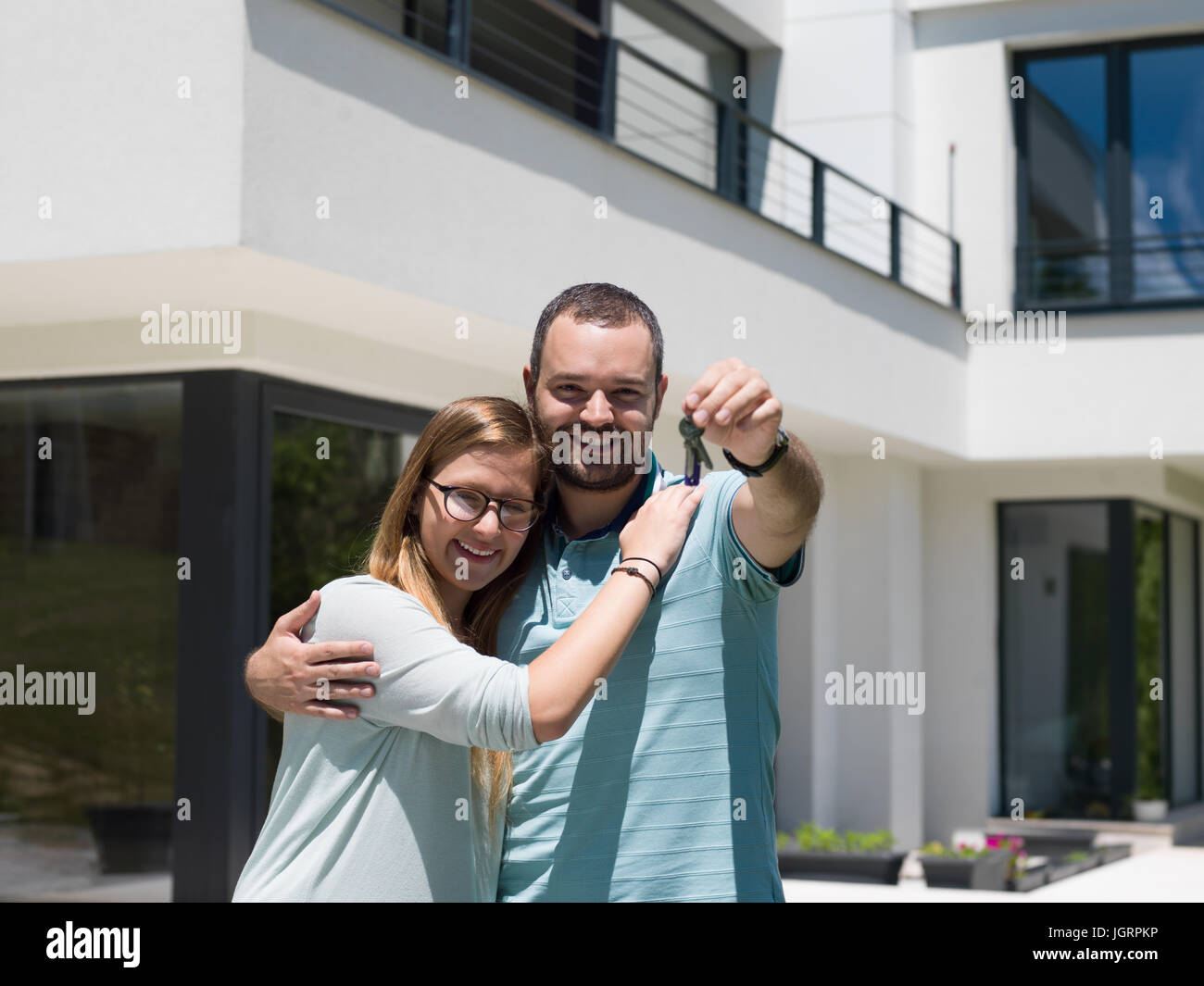 Portrait of a happy young couple hugging in front of their new luxury ...