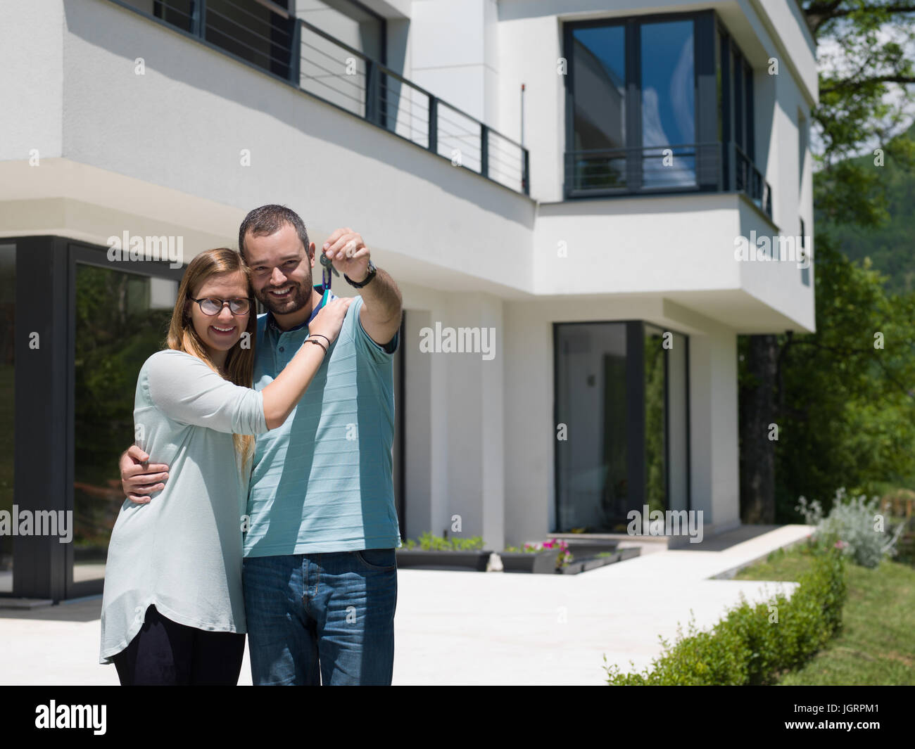 Portrait of a happy young couple hugging in front of their new luxury ...