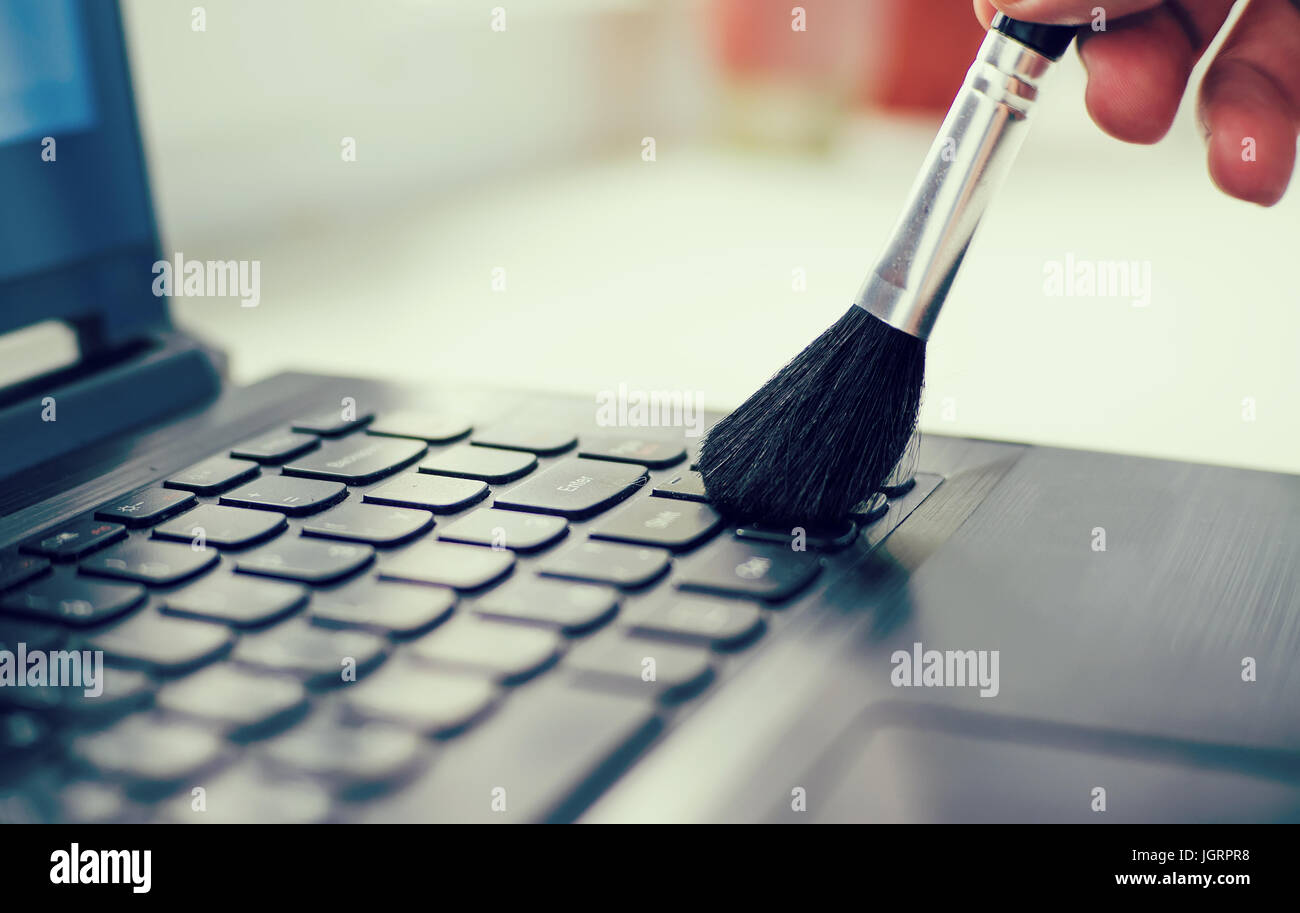 Cleaning keyboard and caring computer. Male hand with a brush to remove dust from the keyboard