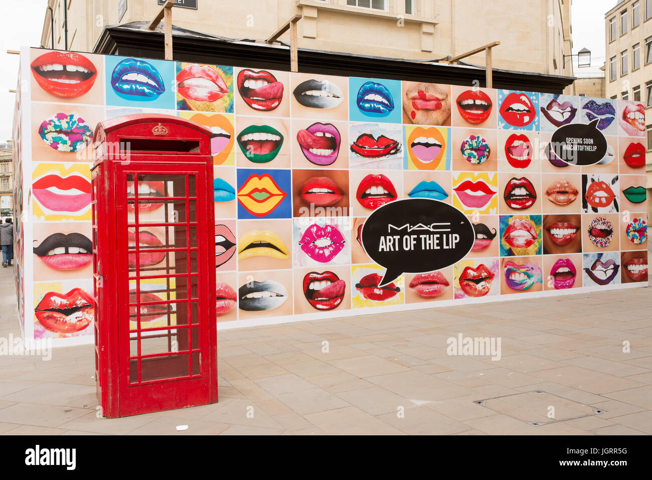 Big billboard on UK high street full of mouths with lipstick next to a red phone booth advertising MAC Cosmetics, stylized as M·A·C, a cosmetics manuf Stock Photo