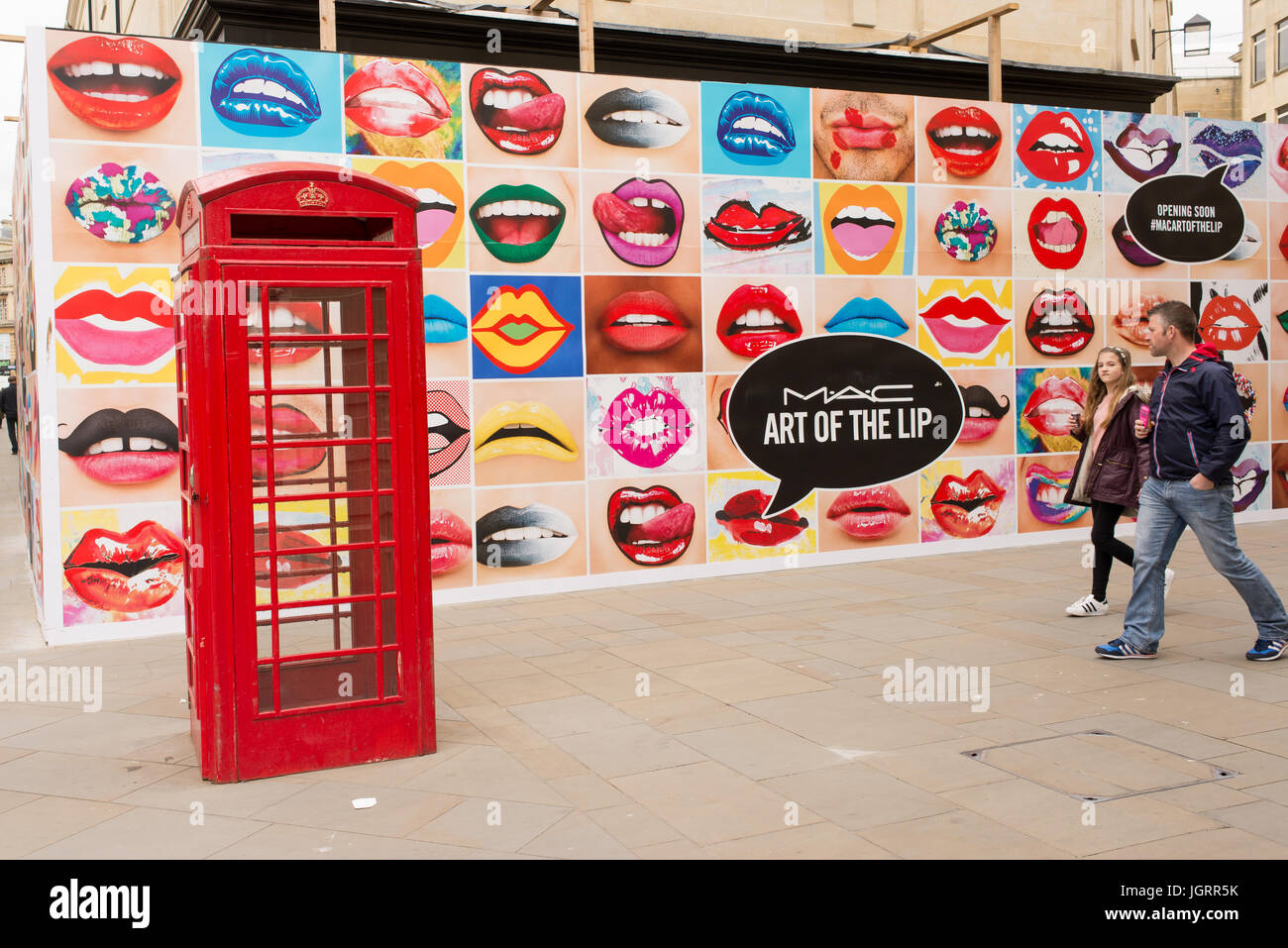 Big billboard on UK high street full of mouths with lipstick next to a red phone booth advertising MAC Cosmetics, stylized as M·A·C, a cosmetics manuf Stock Photo