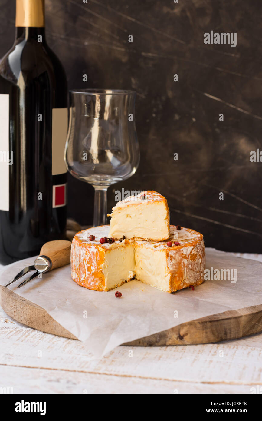 French munster cheese with orange rind, red pepper corns, cut off slice