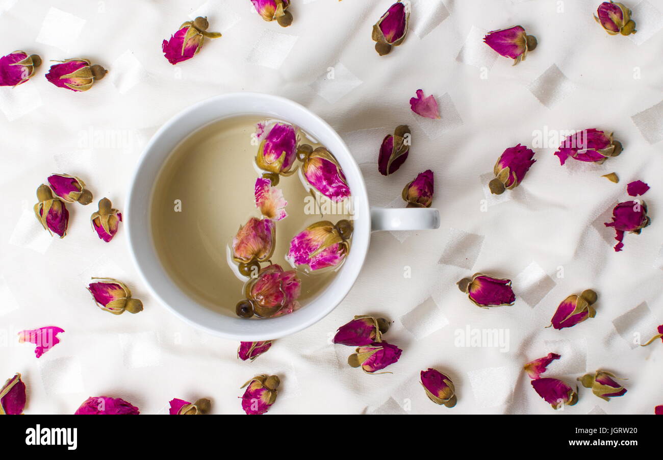 Rose tea in a cup on white fabric Stock Photo