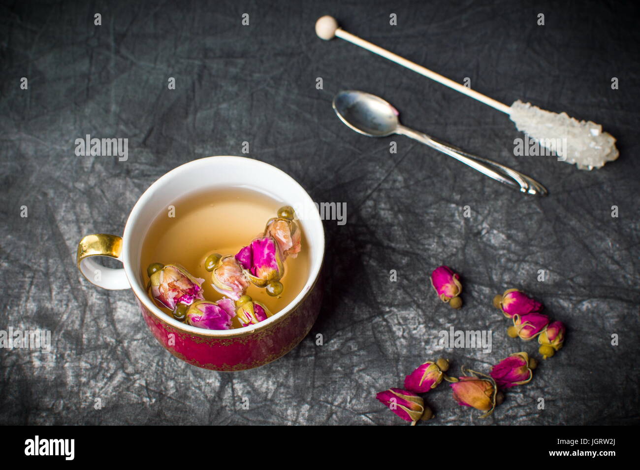 Rose tea in red cup on dark fabric Stock Photo
