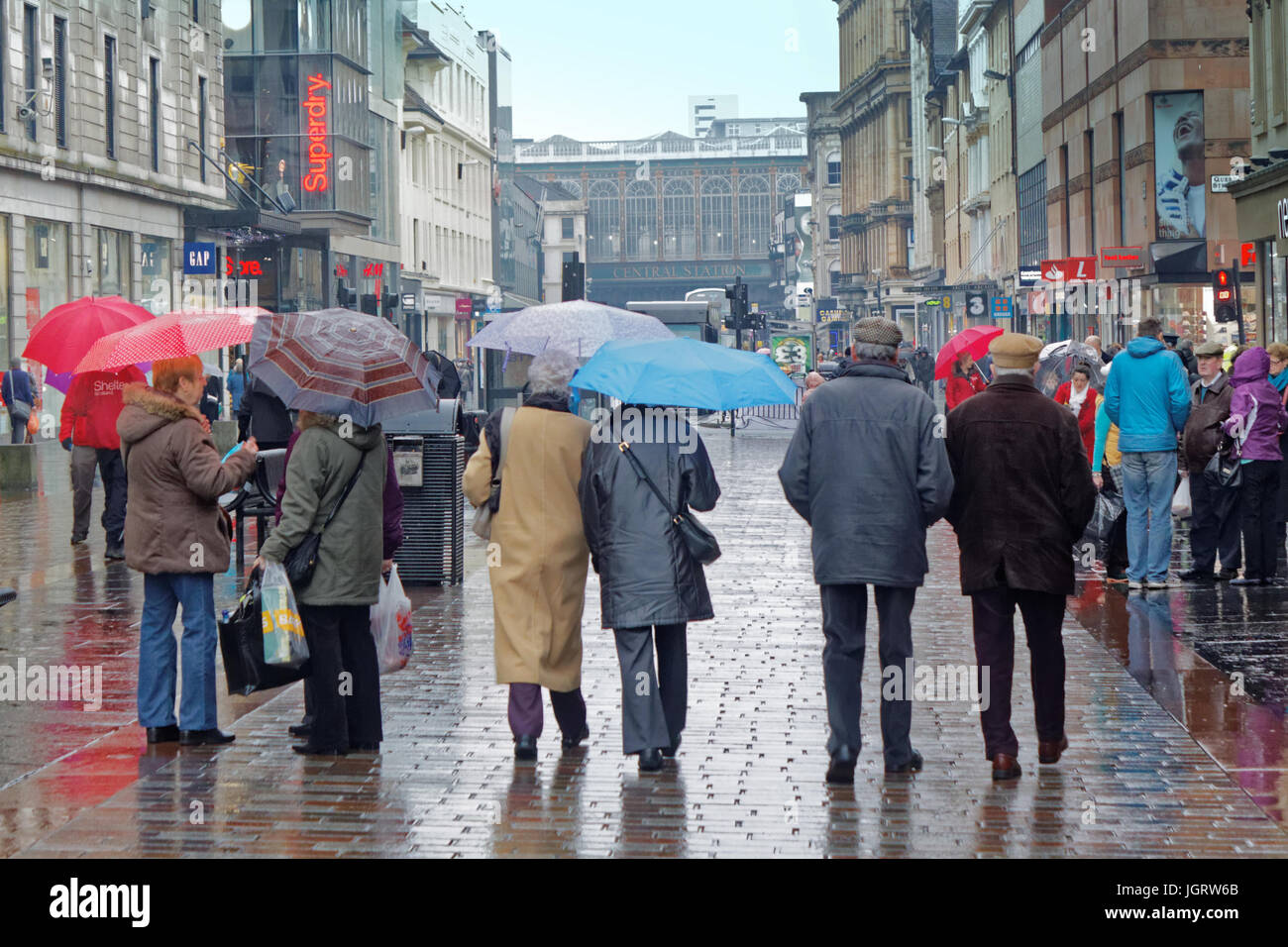 people raining in Glasgow with umbrellas on the reflecting street wet rain day brollie Stock Photo