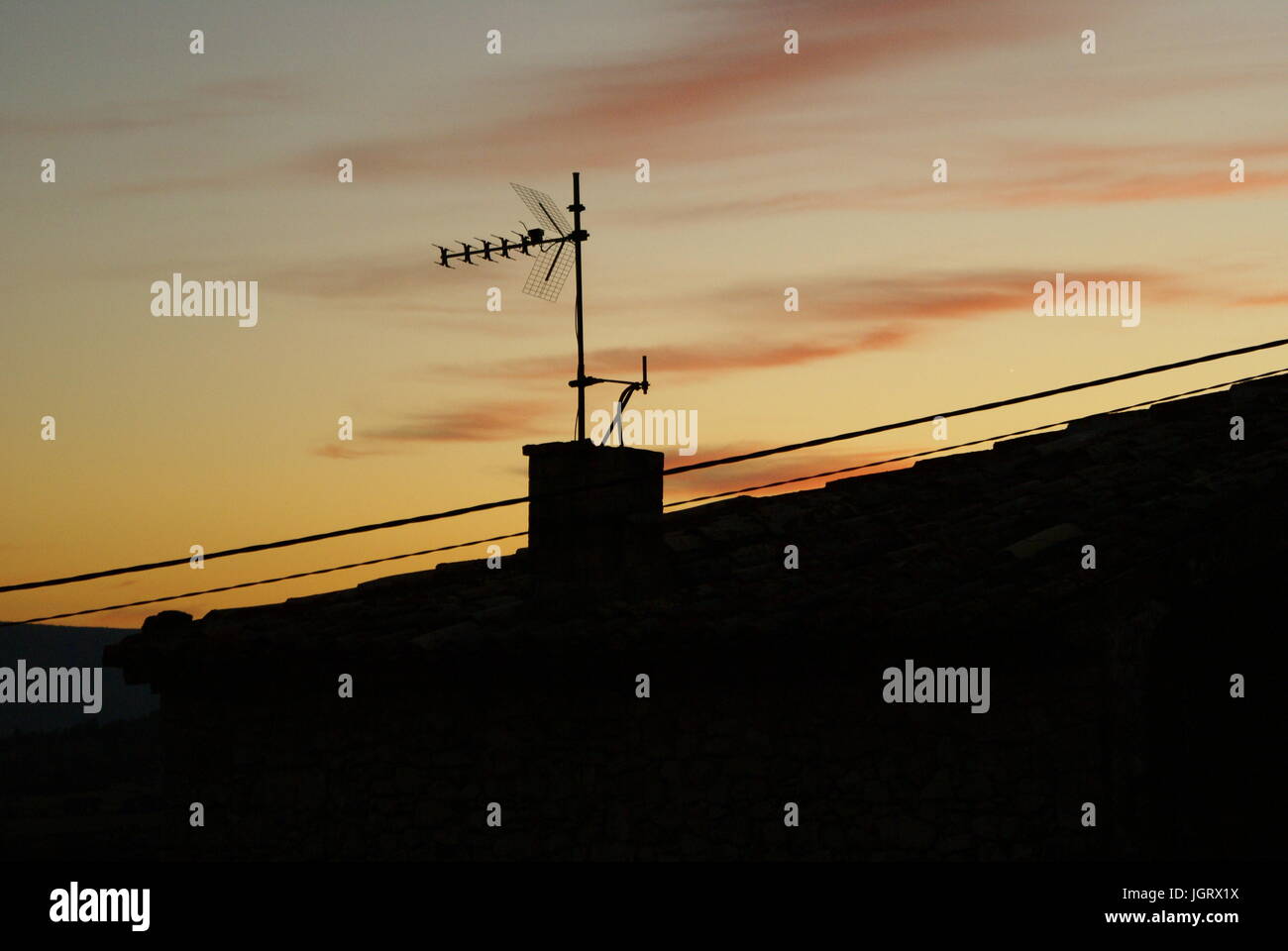 A chimney with an antenna at sunset Stock Photo