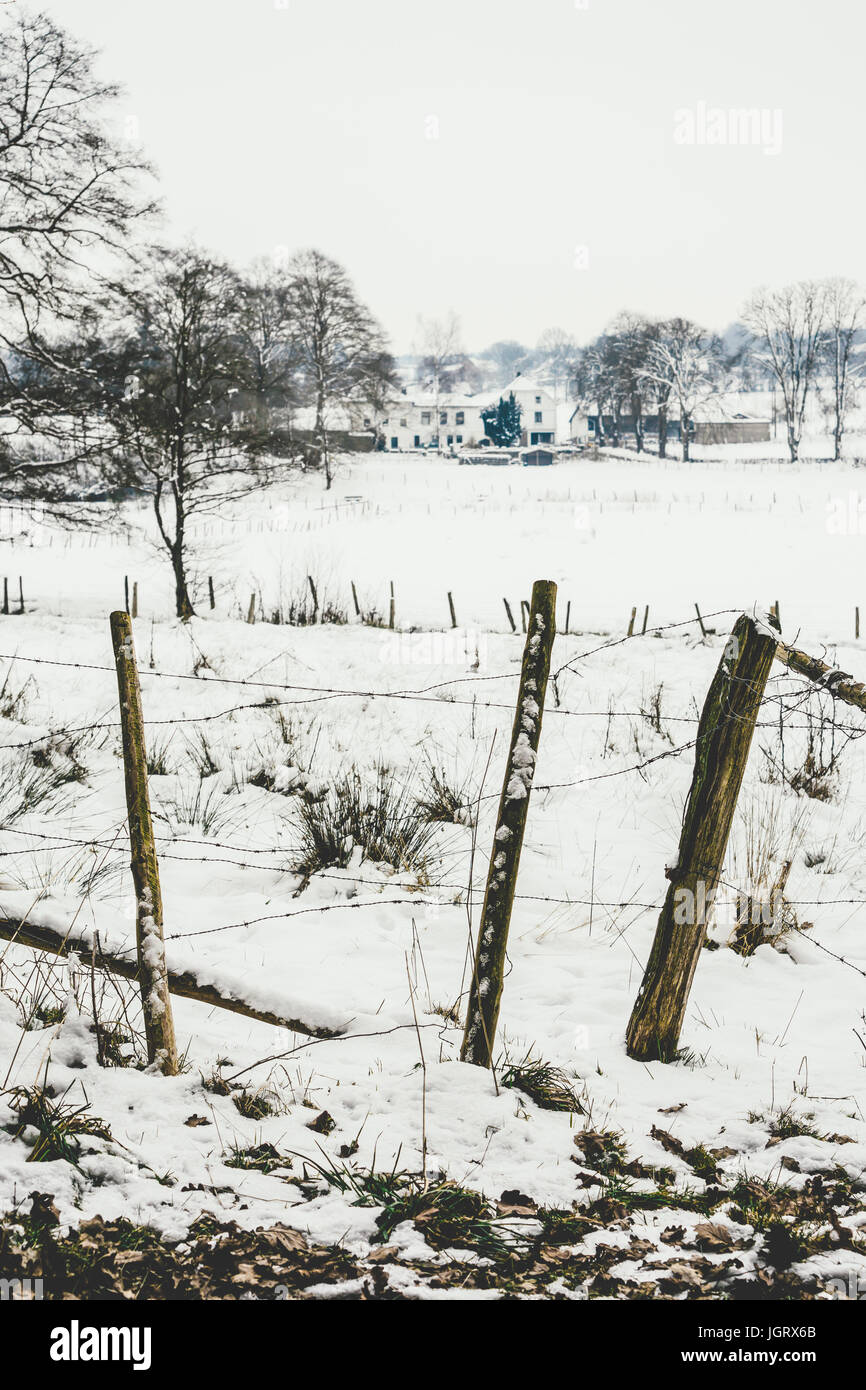 Old fence in a rural field covered in snow in the winter. Stock Photo