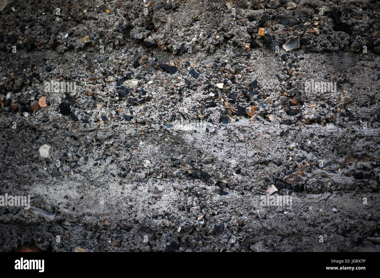 The dark texture of cinder block with coarse rough stones. Exposed aggregate concrete texture background. Concrete wall in grunge style Stock Photo