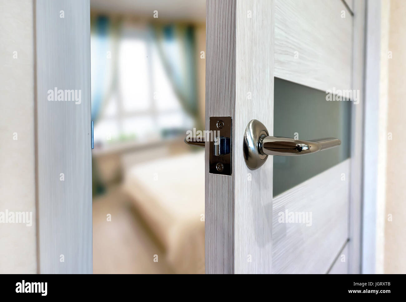 Close-up elements of the interior of the apartment. Ajar white door. Chrome door handle. Stock Photo