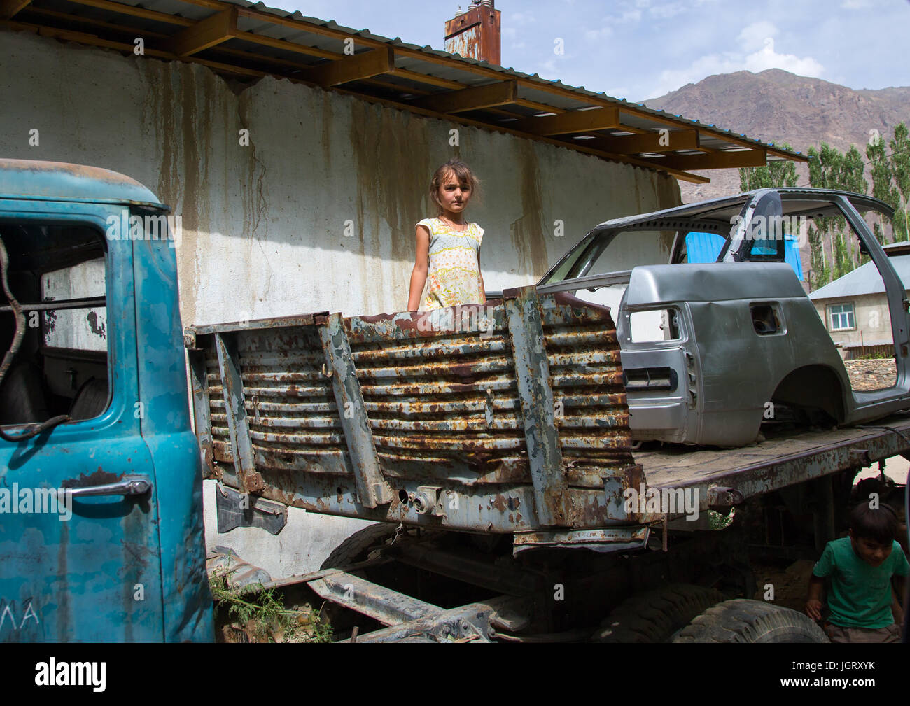 Tajik girl playing in old cars wrecks, Gorno-Badakhshan autonomous region, Khorog, Tajikistan Stock Photo