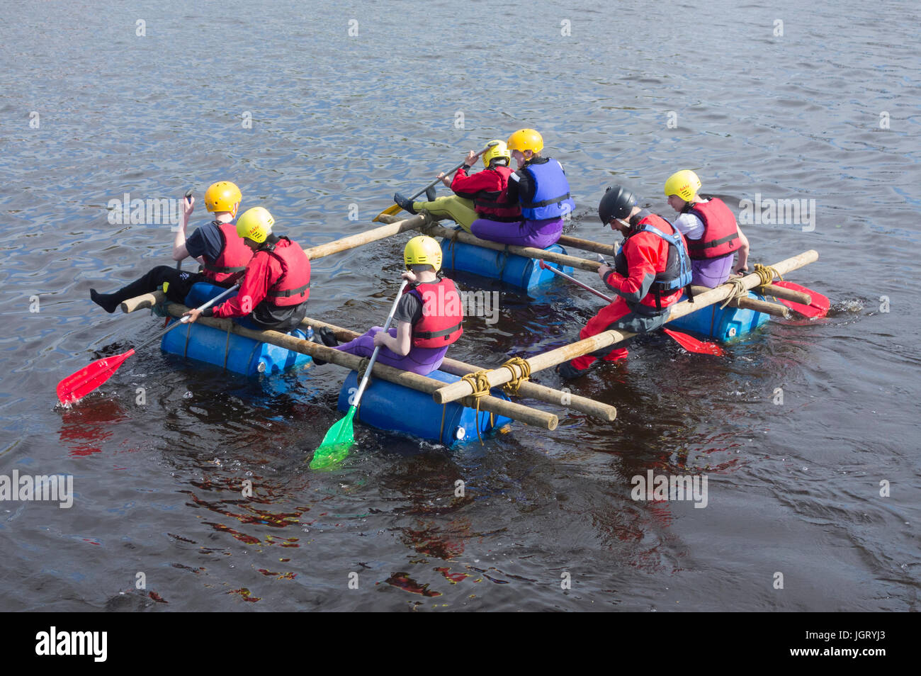 Teenagers launchig raft they have just built on river tees, north east England. UK Stock Photo