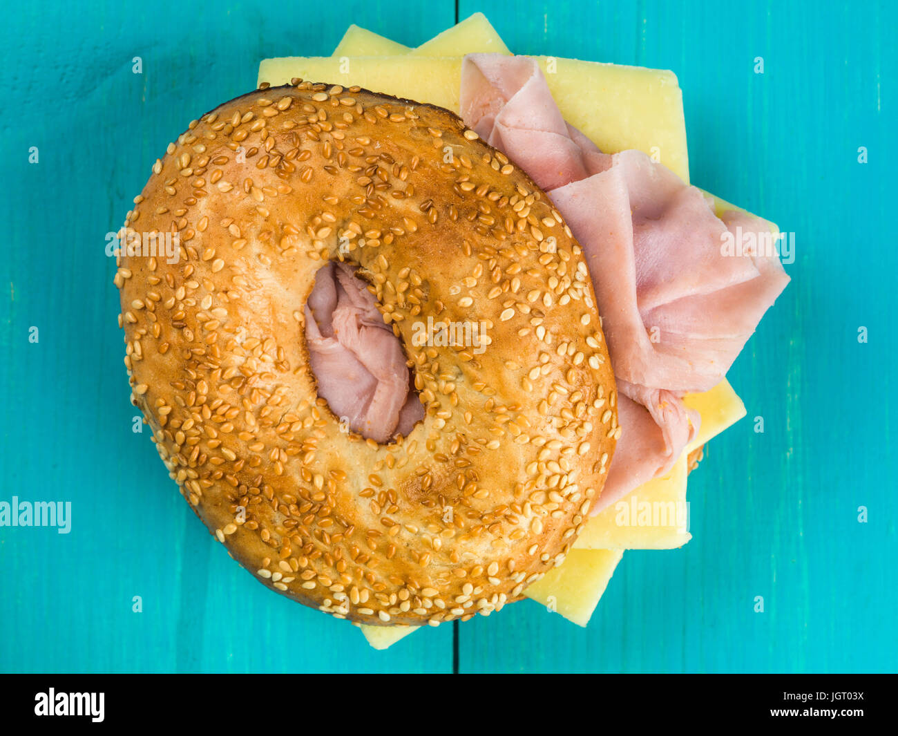 Ham and Cheese Toasted Bagel Against a Blue Background Stock Photo