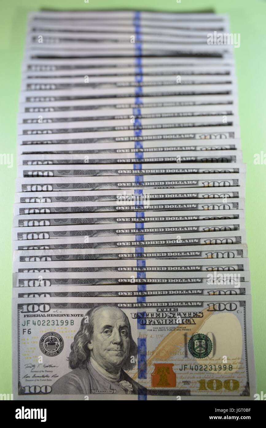 new hundred dollar bills American $100 USD cash money on green background fanned out in a single line Stock Photo