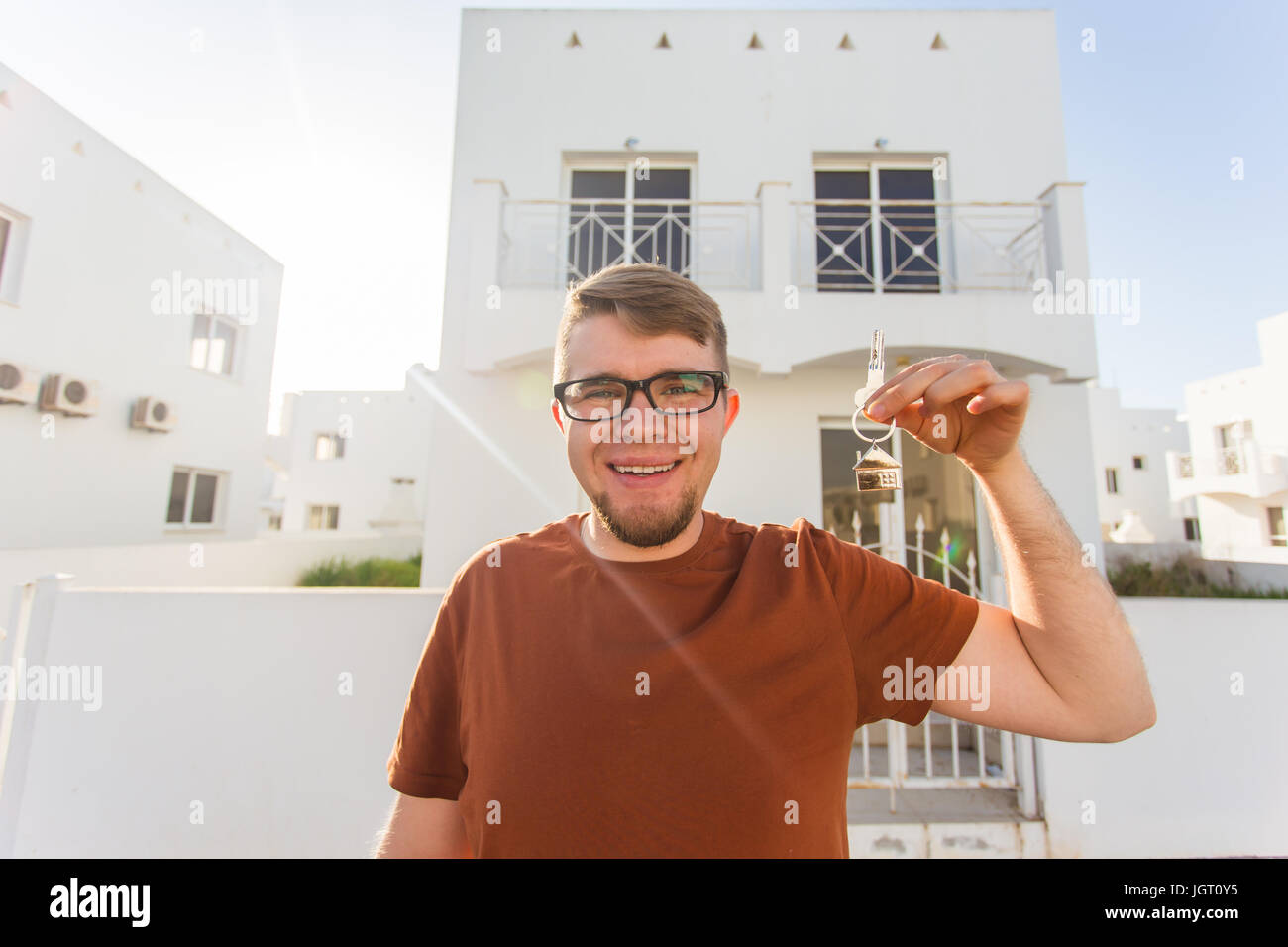 Concept of housewarming, real estate, new home - Young man holding key ...