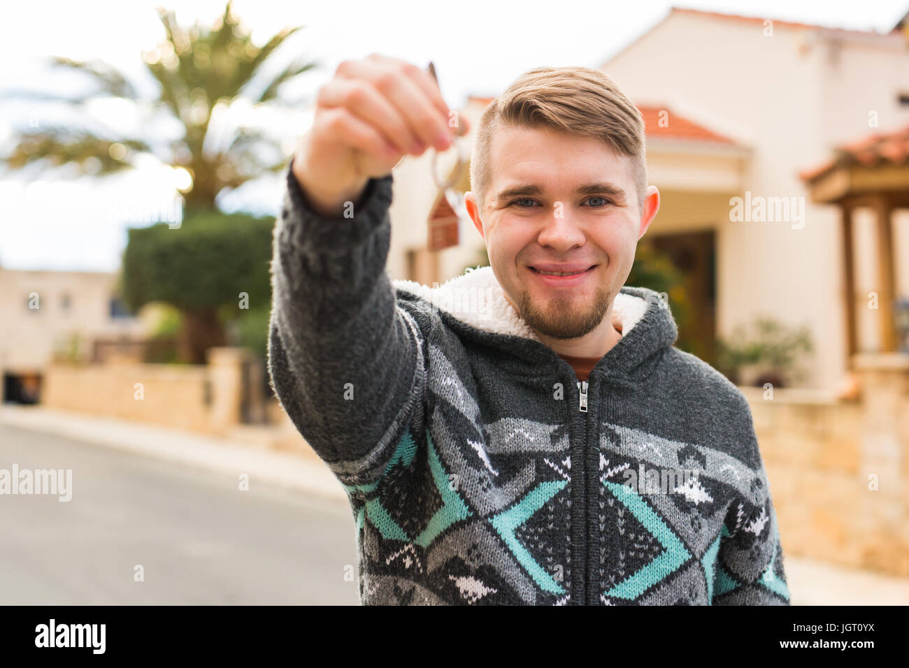 Concept of housewarming, real estate, new home - Young man holding key ...
